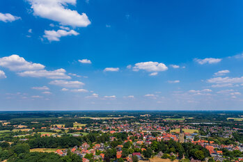 Das Bild zeigt eine Luftbildaufnahme der Gemeinde Emsbüren. Am unteren rechten Rand ist der Kirchturm St. Andreas zu sehen.