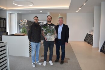 Das Bild zeigt Bürgermeister Bernhard Overberg und Citymanager Klaus Hofschröer bei der Übergabe eines Geschenkes an Stephan Sabel zur Neueröffnung des Unternehmens Fliesen Sabel
